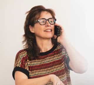 Geertrui van Look al glimlachend aan het bellen met een telefoon in de hand